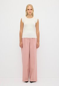 Hladký bílý top s ribbed vzorem a krátkými rukávy, který je kombinován s vysoce pasovými širokými kalhotami v jemně růžové barvě. Hladká tkanina a precizní střih.
