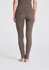 Braune, enganliegende Leggings aus strukturiertem Material mit hohem Taillenbund und knöchellanger Passform. Niedrig geschnittene Passform, keine sichtbaren Metallteile.