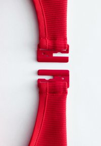 Deux extrémités d'une sangle élastique rouge avec des clips à boucle en plastique, séparées et positionnées sur un fond blanc.