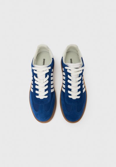 Kék velúr sportcipő fehér fűzőkkel, gumitalppal és csíkos díszítéssel. Lekerekített orr-rész és párnázott belső a kényelemért.