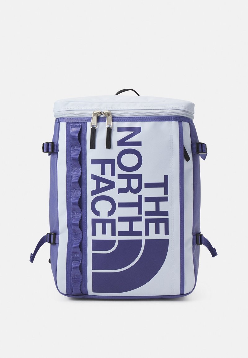 Un sac à dos bleu clair et violet avec un grand logo, des fermetures éclair doubles, des sangles latérales et des accents texturés à l'avant.