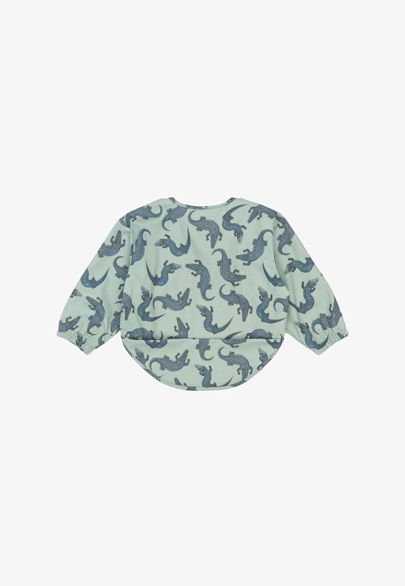 Haut en textile vert clair à manches longues, avec un motif répété de crocodiles bleus. Ourlet arrondi avec poignets élastiques.