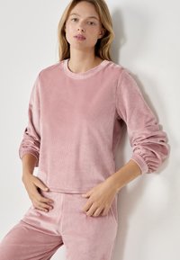 Różowy sweter dresowy z okrągłym dekoltem, lekko skrócona sylwetka i elastyczne rękawy, w komplecie z pasującymi spodniami.