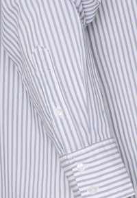 Langarmhemd mit hellblauen und weißen vertikalen Streifen, aus Baumwollstoff, mit knöpfbarem Manschette und gestickten Details auf der Tasche.