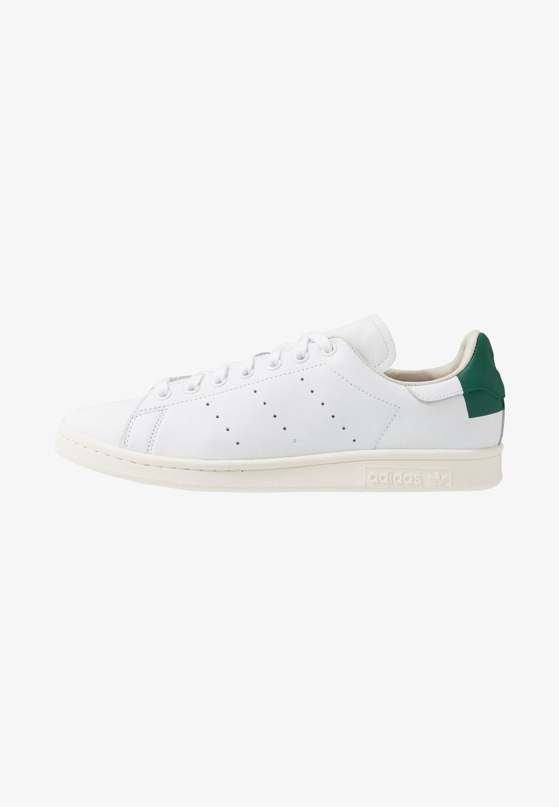 White leather sneaker with green heel accent, lace-up design, perforated side details, and a tan rubber sole. Features adidas branding.