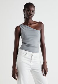 Gray one-shoulder fitted top with a smooth texture, paired with off-white wide-leg jeans, highlighting a minimalist design.