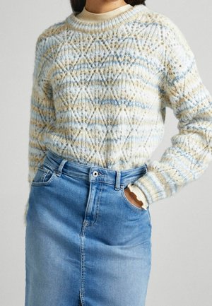 Sweter dziany z geometrycznym wzorem w jasnoniebieskim, kremowym i beżowym kolorze; okrągły dekolt i ściągacze na rękawach w parze z dżinsową spódnicą.