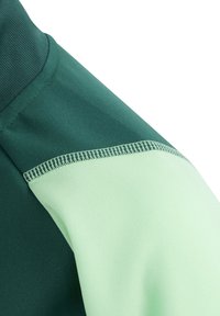 Grüner und mintgrüner Sweatshirt-Ärmel, mit einer glatten Textur, kontrastierenden Stoffabschnitten und sichtbaren Nähdetails.