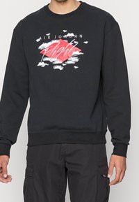 Black sweatshirt with a crew neck, featuring a colorful graphic design of clouds and a diamond with "AIR JORDAN Flight" in white letters.