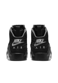 Černé tenisky Nike s hladkým textilním svrškem, polstrovanými límci a stříbrným logem 'NIKE AIR' na patě. Gumové podrážky s texturovaným gripem.