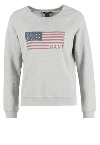 Grå sweatshirt lavet af blødt stof, der har et stort amerikansk flag grafik i blå og rød. Ribbet halsudskæring og manchetter.