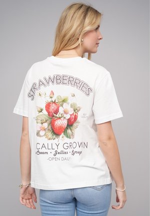 White cotton t-shirt featuring a colorful strawberry graphic with floral accents on the back. Short sleeves and relaxed fit.