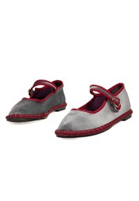 Par de zapatos Mary Jane de gamuza gris con ribetes, correas y detalles de costura en rojo sobre suelas negras, mostrados sobre fondo blanco.