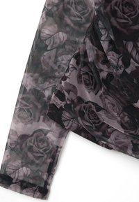 Top de malla transparente con un patrón floral de rosas en tonos de gris y negro, con lados fruncidos y textura suave.