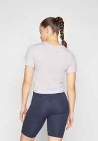 Camisa de cuello redondo de manga corta en un tono púrpura claro, combinada con pantalones cortos de ciclismo de talle alto en color marino. Tejido suave, diseño ajustado y sin patrones visibles.