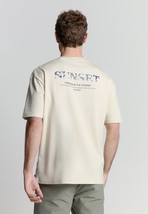 Beige katoenen T-shirt met ronde hals, korte mouwen en een grafische print op de achterkant met tekst in blauw en grijs.