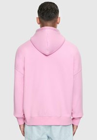 Pink hooded sweatshirt with a relaxed fit, featuring long sleeves, ribbed hem, and soft texture. Back view shows seamless hood design.