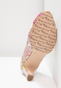 Chaussure à talon haut à motif floral inclinée pour montrer la semelle avec le logo "Tamaris" et l'inscription de la taille 37 sur une surface blanche.