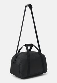 Borsa a duffel nera realizzata in tessuto resistente, con tracolla regolabile e due manici superiori, forma arrotondata e chiusura con zip.