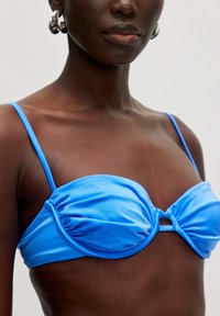 Bikini-Oberteil in Blau aus glattem Stoff, mit einem gerafften Design, dünnen Trägern und einem Knoten-Detail vorne.