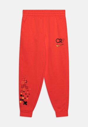Pantalones de chándal rojos hechos de una tela suave, con los logos de "CR7" y Nike en negro, y un patrón gráfico colorido cerca del dobladillo. Cintura elástica.