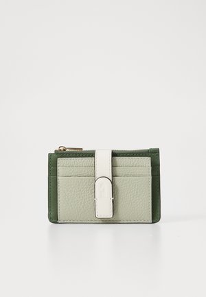 Leather wallet featuring textured sage green and dark green panels, a white strap closure, and card slots on the front.