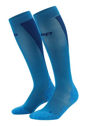 Calze a compressione blu con un design a gradiente, caratterizzate da motivi a trama sulla punta e sul tallone, e zone rinforzate per il supporto.