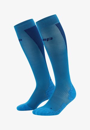 Blaue Kompressionssocken mit einem Farbverlauf-Design, ausgestattet mit strukturierten Mustern an Zehen und Ferse sowie verstärkten Bereichen für zusätzliche Unterstützung.