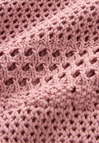 Nahaufnahme von weichem, rosa gestricktem Stoff mit einem offenen, strukturierten Muster, das ein erhöhtes, honigwabenähnliches Design erzeugt.