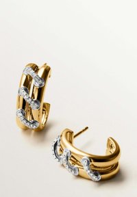 Pendientes de aro en oro y plata con un diseño entrelazado, que cuenta con acentos claros y un acabado pulido. Forma simple y moderna; cierre de tipo presión.