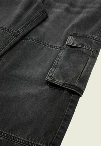 Schwarze Denimjacke mit weicher Textur, ausgestattet mit einem Kragen, geknöpften Bündchen und sichtbaren Nähdetails. Leicht ausgewaschener Look, modernes Design.