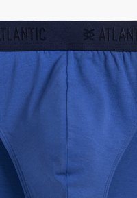 Niebieskie bawełniane slipy z ciemnoniebieskim elastycznym pasem, na którym wytłoczona jest nazwa marki "ATLANTIC". Gładka tekstura.