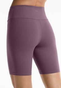 Höga lila shorts tillverkade av elastiskt material, med en slät yta och en logotyp på midjebandet, utformade för komfort och rörelse.