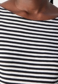 Schwarz-weiß gestreiftes Shirt mit weitem Ausschnitt. Der Stoff wirkt glatt und leicht, mit gleichmäßig verteilten horizontalen Streifen.