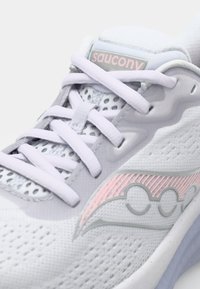 Chaussure de sport blanche avec une tige en maille, des accents gris et un logo rose. Caractéristiques : lacets plats, détails perforés et semelle rembourrée.