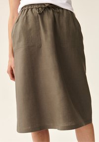 Khaki-linnekjol med elastisk midjebånd og snøring, med to frontlommer og en rett, knelengde silhuett.