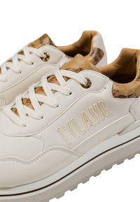Zapatillas color crema con cordones blancos, con el texto grabado "1ª CLASSE" en el lateral y detalles de cuero marrón que presentan un sutil diseño de mapa.