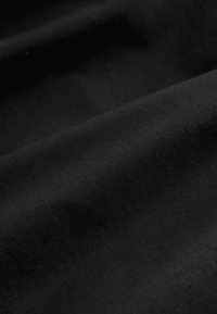 Gros plan sur un tissu noir lisse avec une texture visible et des plis doux.