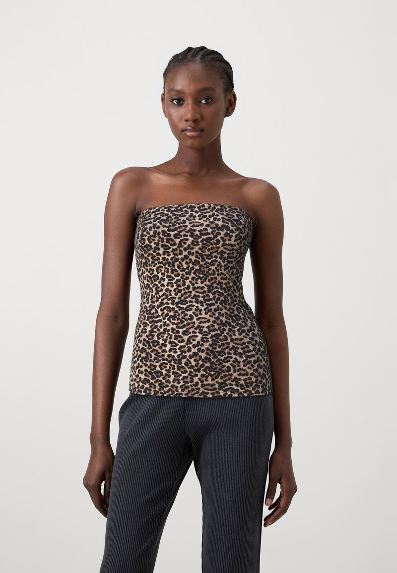 Top bez ramiączek w brązowy wzór w panterkę o dopasowanym kroju, wykonany z gładkiego materiału. Połączony z ciemnymi prążkowanymi spodniami.