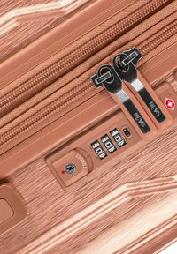 Hartschalenkoffer in Roségold mit kontrastierendem silbernem Reißverschluss. Verfügt über ein Zahlenschloss und eine strukturierte Oberfläche für besseren Grip.