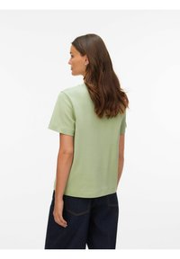 Kortærmet, lysegrøn top lavet af glat stof. Boxy pasform med lige kant, uden synlige mønstre eller detaljer. Båret med mørke jeans.