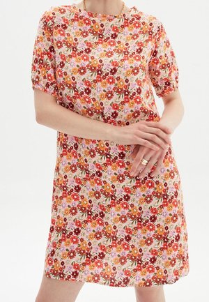 Robe florale avec des manches courtes, un col rond, et un fond rose clair avec des fleurs rouges, orange et violettes dans un motif répétitif.