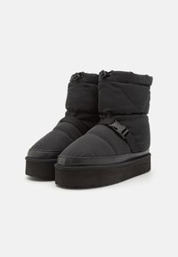 Pair of black insulated winter boots with thick soles, adjustable straps, and elastic drawstring closures at the top.