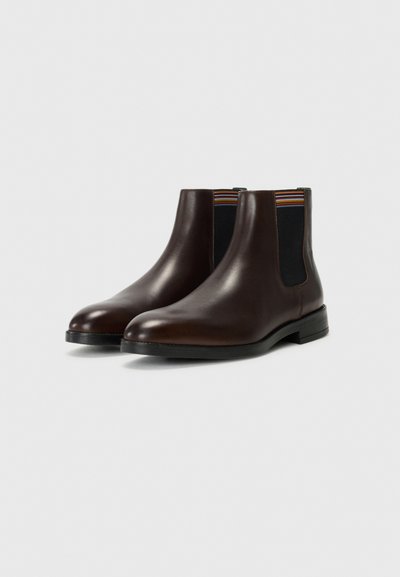 Botas Chelsea de cuero marrón con paneles laterales elásticos en negro y rayas multicolores. Punta redondeada y tacón bajo y plano. Textura suave.