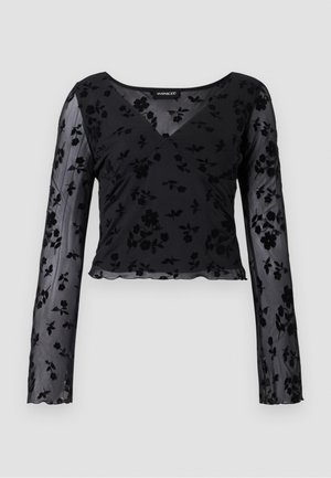 Haut à manches longues noir en tissu transparent avec un motif floral, décolleté en V et ourlet festonné. Détail de design croisé à l'avant.