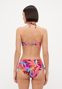 Spalvingas bikinis, turintis v-kaklo dizainą ir aukštu liemeniu. Tropinių lapų raštas rožinės, mėlynos ir geltonos spalvų tamsiame fone.
