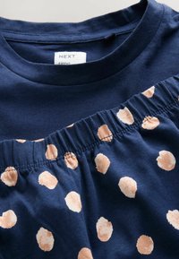 Camisa de algodón azul marino con escote redondo y tela a juego azul marino con lunares beige y fruncido elástico.