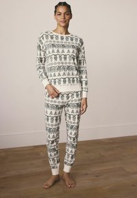 Koordiniertes Schlafanzugset in Creme mit schwarzem Wintermotiv. Langärmliges Oberteil und taillierte Hose mit gerippten Bündchen. Weicher Stoff.