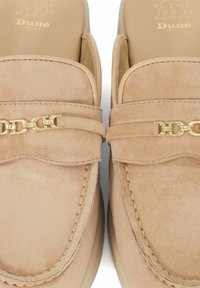 Nude suède loafers met een kettingaccent, voorzien van gestikte details en een gladde binnenvoering. Ontwerp met een platte zool voor gemakkelijk dragen.