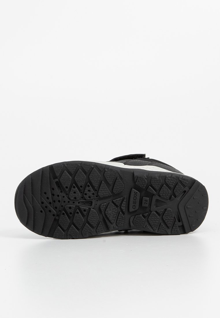 Schwarze Gummisohle mit strukturiertem Profil, die verschiedene Formen und Aussparungen für Grip und Flexibilität aufweist. Enthält Markendetails.